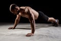 Young powerful sportsman training push ups over dark background.