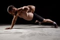 Young powerful sportsman training push ups over dark background.