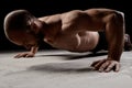 Young powerful sportsman training push ups over dark background.