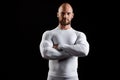 Young powerful sportsman in white clothing over black background.