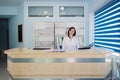 Young practitioner doctor working at the clinic reception desk, she is answering phone calls and scheduling appointments Royalty Free Stock Photo