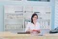 Young practitioner doctor working at the clinic reception desk, she is answering phone calls and scheduling appointments Royalty Free Stock Photo