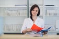 Young practitioner doctor working at the clinic reception desk, she is answering phone calls and scheduling appointments Royalty Free Stock Photo