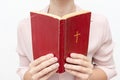 Young praying christian woman`s hands holding holy bible with a cross on a cover Royalty Free Stock Photo