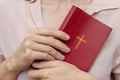 Young praying christian woman`s hands holding holy bible with a cross on a cover Royalty Free Stock Photo