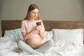 Young preganant woman expecting a baby relaxing on bed indoors Royalty Free Stock Photo