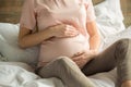 Young preganant woman expecting a baby relaxing on bed indoors Royalty Free Stock Photo