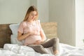 Young preganant woman expecting a baby relaxing on bed indoors Royalty Free Stock Photo