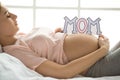 Young preganant woman expecting a baby relaxing on bed indoors Royalty Free Stock Photo