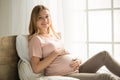 Young preganant woman expecting a baby relaxing on bed indoors Royalty Free Stock Photo