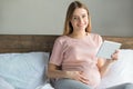 Young preganant woman expecting a baby relaxing on bed indoors Royalty Free Stock Photo