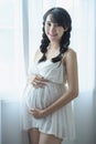 Young Pregnant Asian Woman Holds Her Hands on Her Swollen Belly, Love Concept. Royalty Free Stock Photo