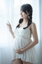 Young Pregnant Asian Woman Holds Her Hands on Her Swollen Belly, Love Concept. Royalty Free Stock Photo