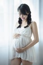 Young Pregnant Asian Woman Holds Her Hands on Her Swollen Belly, Love Concept. Royalty Free Stock Photo