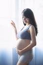 Young Pregnant Asian Woman Holds Her Hands on Her Swollen Belly, Love Concept. Royalty Free Stock Photo