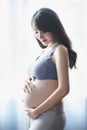 Young Pregnant Asian Woman Holds Her Hands on Her Swollen Belly, Love Concept. Royalty Free Stock Photo