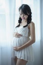 Young Pregnant Asian Woman Holds Her Hands on Her Swollen Belly, Love Concept. Royalty Free Stock Photo