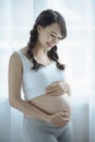 Young Pregnant Asian Woman Holds Her Hands on Her Swollen Belly, Love Concept. Royalty Free Stock Photo