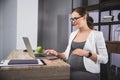 Young pregnant business woman using a laptop in the office Royalty Free Stock Photo