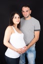 Young pregnant couple expecting baby waiting in love in black background