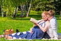 Young pregnant couple in a park reading a book about pregnancy Royalty Free Stock Photo