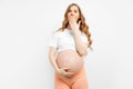 Pregnant emotionally surprised woman standing with her mouth open on a white background. Human emotions