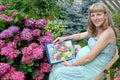 The young pregnant female artist shows drawing of a blossoming hydrangea