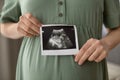 Young pregnant female holding sonogram picture of her unborn baby