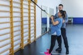 Young pregnant female training in fitness club with modern TRX equipment during effective full body workout with personal trainer Royalty Free Stock Photo