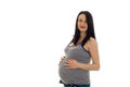 Young pregnant girl with dark hair touching her big belly and looking at the camera isolated on white background Royalty Free Stock Photo