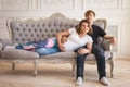 Young pregnant girl lying on sofa and hugging with handsome husband in room Royalty Free Stock Photo