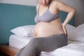 Pregnant woman  having waist pain and sitting on bed Royalty Free Stock Photo