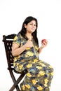 Young pregnant lady is holding apple in hand and sitting on the chair Royalty Free Stock Photo