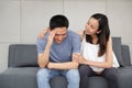 Young pregnant wife comforting and touching shoulder young husband while sitting on sofa