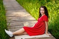 A young pregnant woman in a beautiful red dress with a bouquet of daisies. An active girl during pregnancy. Portrait fashion