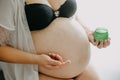 Young pregnant woman with the belly smearing cream against stretch marks, pregnancy concept Royalty Free Stock Photo