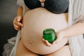 Young pregnant woman with the belly smearing cream against stretch marks, pregnancy concept Royalty Free Stock Photo