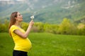 Young pregnant woman blowing dandelion seeds on a meadow Royalty Free Stock Photo