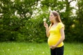 Young pregnant woman blowing dandelion seeds on a meadow Royalty Free Stock Photo