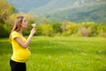 Young pregnant woman blowing dandelion seeds on a meadow Royalty Free Stock Photo