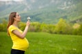 Young pregnant woman blowing dandelion seeds on a meadow Royalty Free Stock Photo