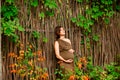 Young pregnant woman in brown dress standing in the autumn park and holding pregnant belly. Royalty Free Stock Photo