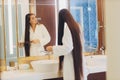 Young pregnant woman brushes long hair in a bathroom. Royalty Free Stock Photo