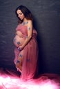 Young pregnant woman with butterflies on her body stands behinde black wall. Beautiful pregnancy