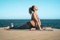 Young pregnant woman doing prenatal pilates exercises session next the sea Royalty Free Stock Photo