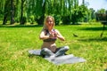 Young pregnant woman doing sport exercises on green grass in the park. Royalty Free Stock Photo