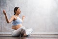 Young pregnant woman doing yoga exercises and meditating at home. Health care, mindfulness, relaxation and wellness