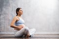 Young pregnant woman doing yoga exercises and meditating at home. Health care, mindfulness, relaxation and wellness