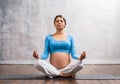 Young pregnant woman doing yoga exercises and meditating at home. Health care, mindfulness, relaxation and wellness