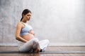 Young pregnant woman doing yoga exercises and meditating at home. Health care, mindfulness, relaxation and wellness